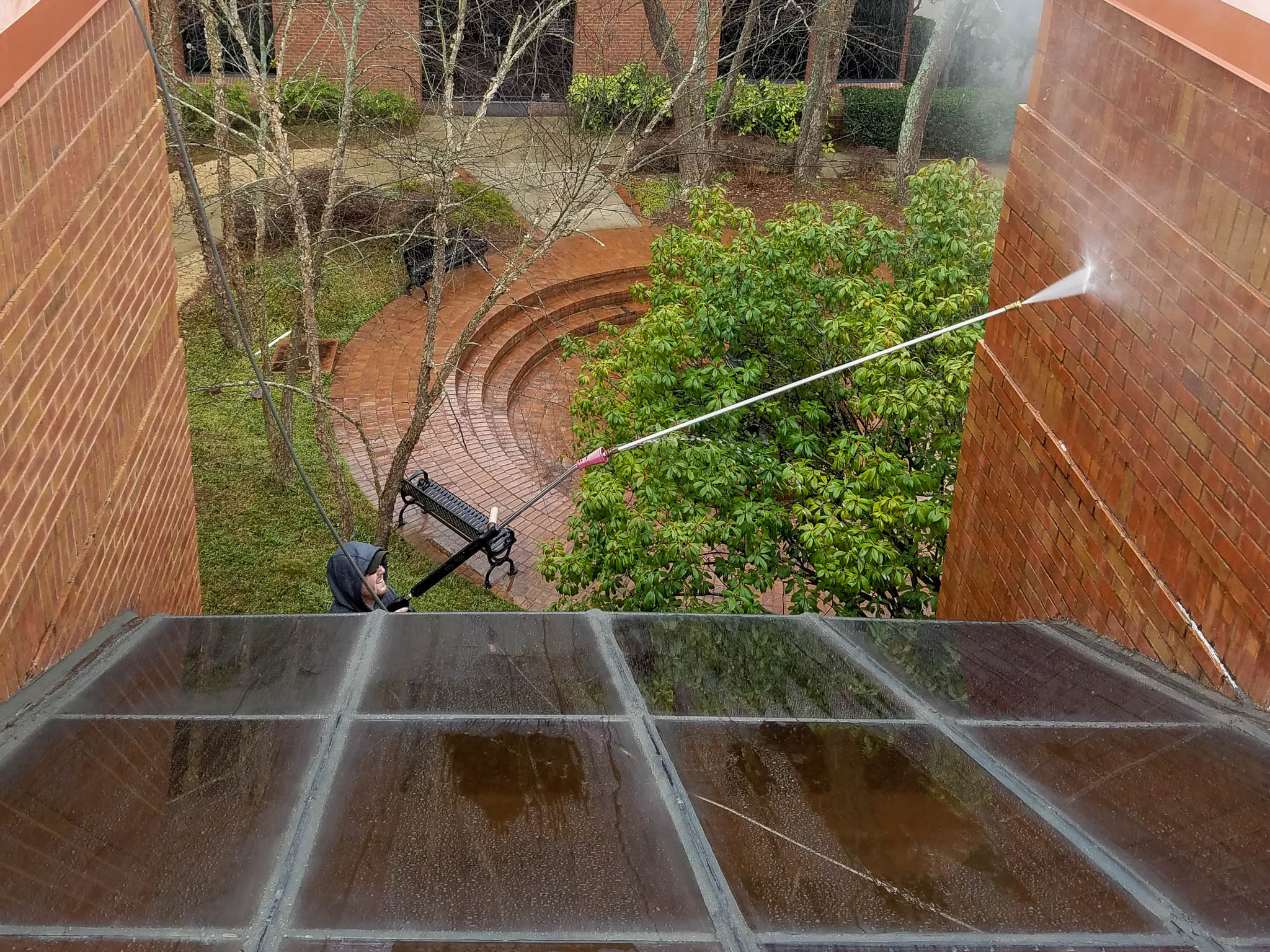 Penson Pressure Washing team member pressure washing a brick office building.